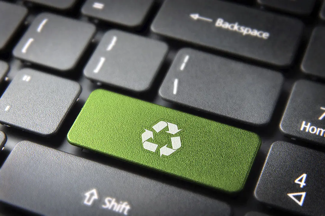 A computer keyboard with a recycle logo on a green key portrays environmentally friendly repurpose of computer equipment.