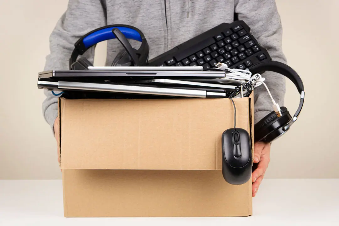 I man holds a box of old used computers and accessories ready to recycle on Earth Day.