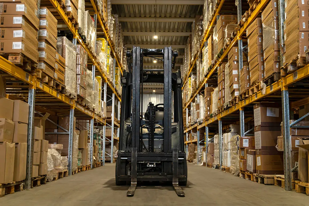 A close up of the front of a forklift in a warehouse.